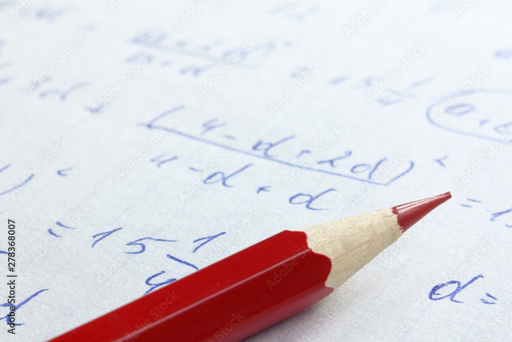 sharpened red pencil on the background of mathematical formulas in notebook close up. checking and solving problems sharpened red pencil on the background of mathematical formulas in notebook close up. checking and solving problems