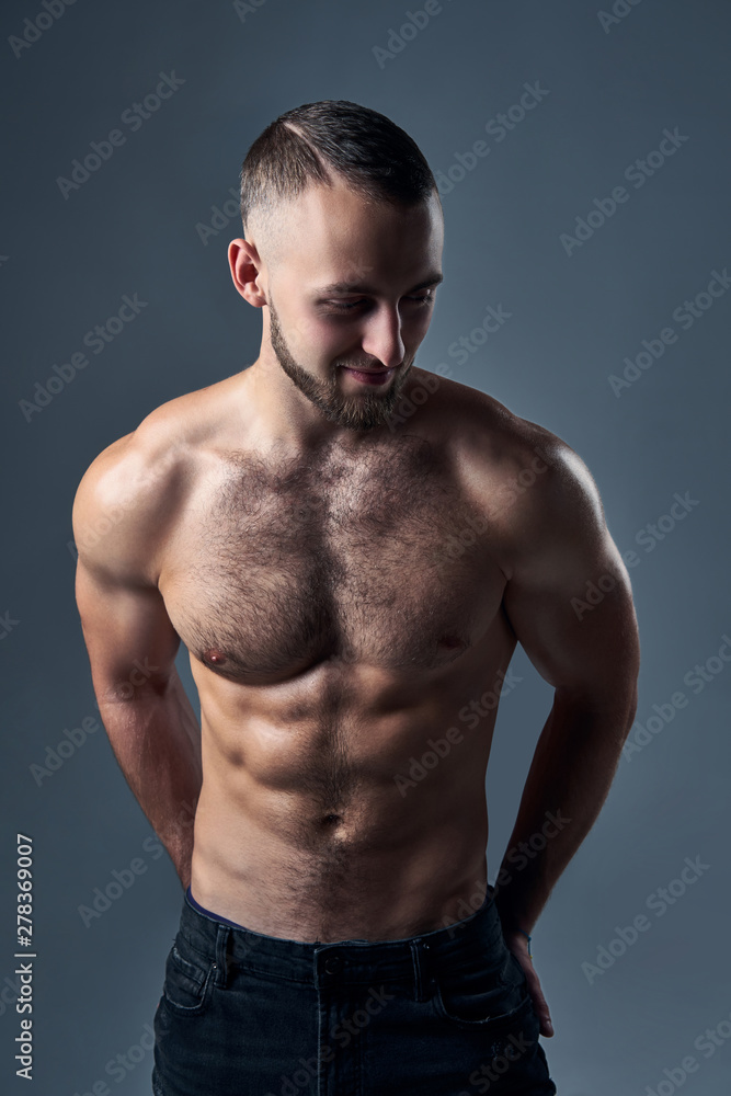 Muscular shirtless man standing with hands in pockets