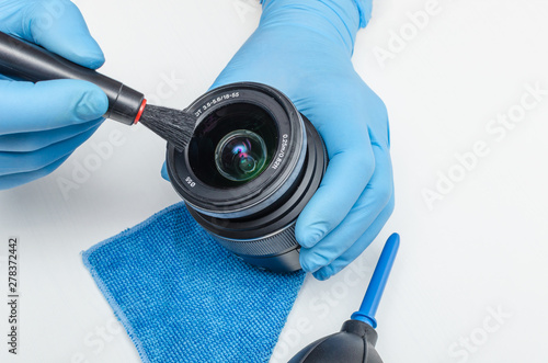 Cleaning the lens of a digital camera and the front lens of contamination with a brush. Maintenance of digital cameras. photo