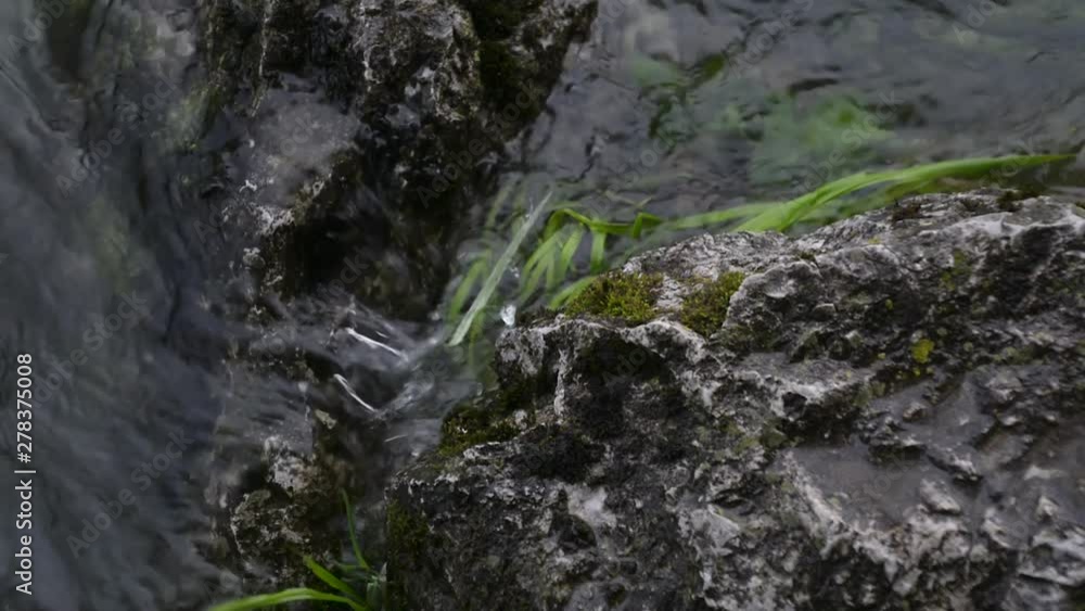 River gently flows towards grass covered rock River gently flows towards grass covered rock