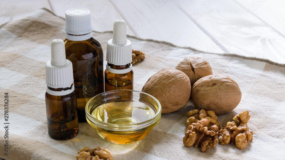 walnut oil with nuts on a light wooden table walnut oil with nuts on a light wooden table
