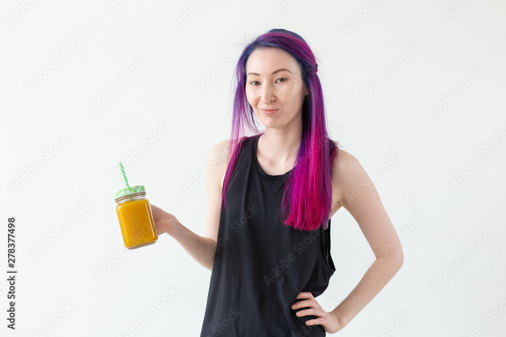 Cute young mixed race hipster girl with colored hair drinks fruit smoothie before starting a yoga class on a white background. Healthy lifestyle concept. Copyspase. Cute young mixed race hipster girl with colored hair drinks fruit smoothie before starting a yoga class on a white background. Healthy lifestyle concept. Copyspase.
