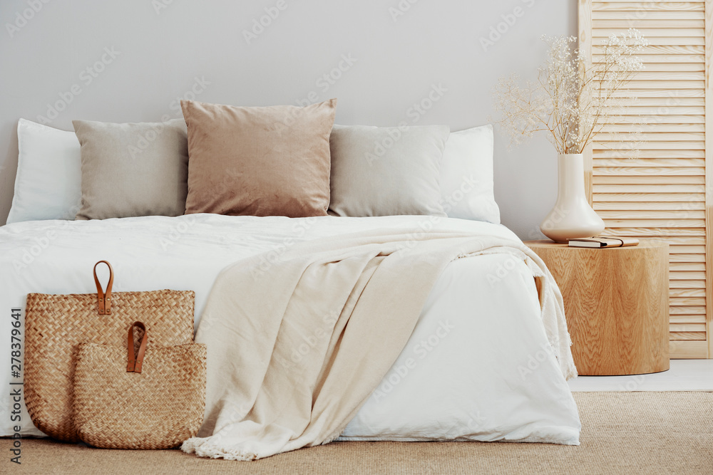 White and beige bedding on double bed in simple interior - obrazy, fototapety, plakaty 