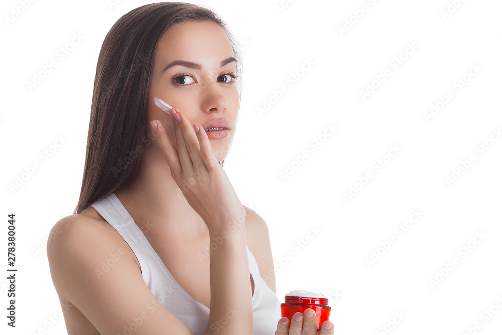 Closeup portrait of young attractive woman applying face cream. Female holding a jar with moisturizing face cream. Closeup portrait of young attractive woman applying face cream. Female holding a jar with moisturizing face cream.