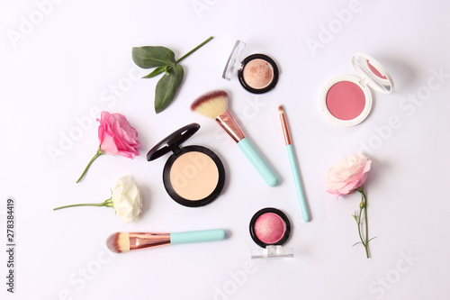 Cosmetics and flowers on a light background top view.