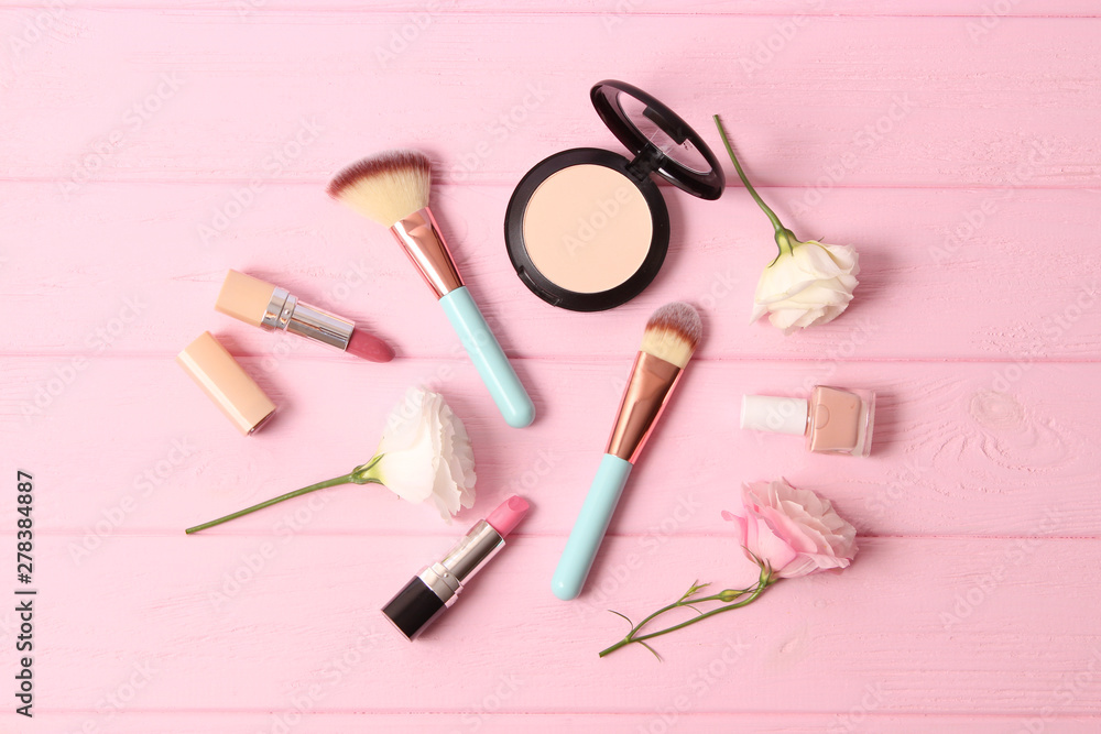 Naklejka premium cosmetics and flowers on a colored background top view.