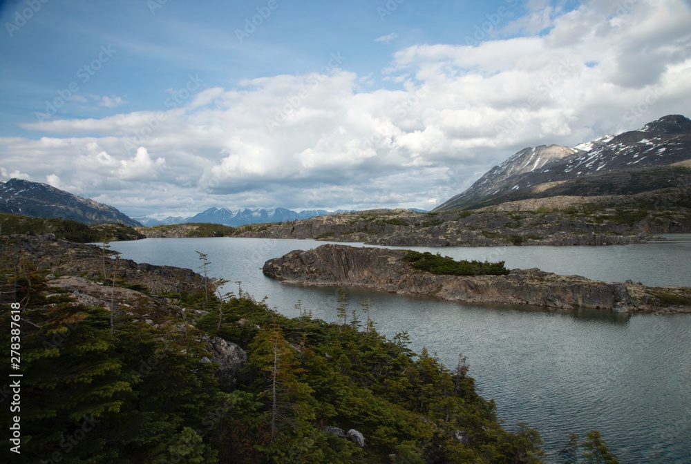 Focus on lakes created by snowy Mountains along Klondike Highway outside White Pass Summit, with blue sky and clouds