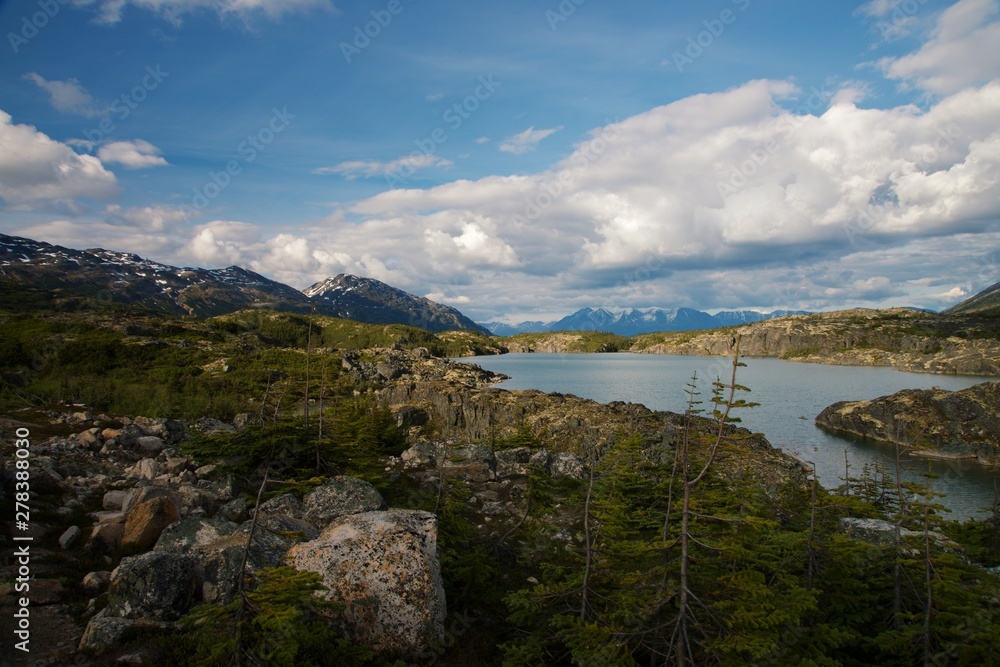 Focus on lakes created by snowy Mountains along Klondike Highway outside White Pass Summit, with blue sky and clouds