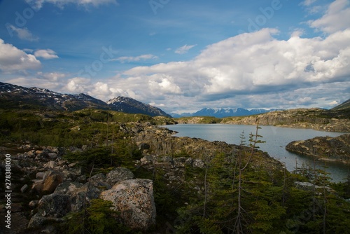 Focus on lakes created by snowy Mountains along Klondike Highway outside White Pass Summit, with blue sky and clouds