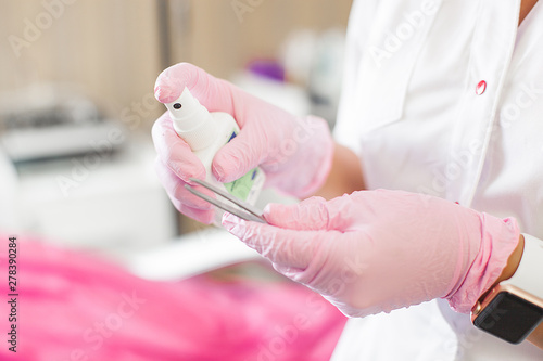 Unrecognizable doctor cleaning and disinfecting tools. Antibacterial agent in the hands close up. Cosmetologist disinfecting her hands in latex gloves before prosedure. photo