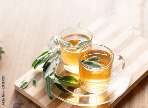 Sage tea infusion with sage leaves on wooden board