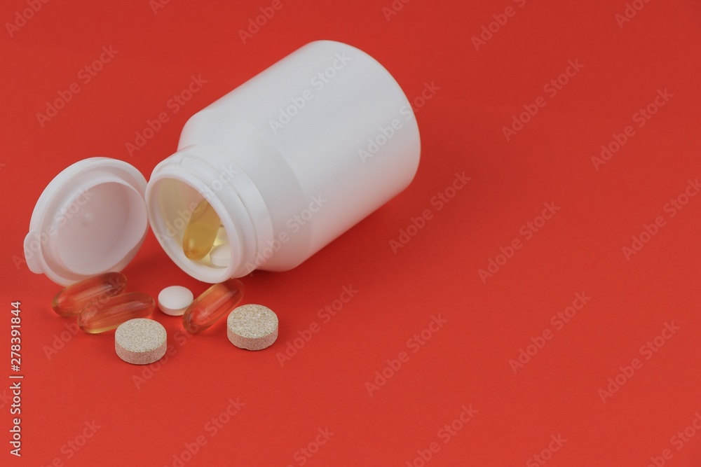 Pills pills in a white jar loose on a red background. Pills pills in a white jar loose on a red background.