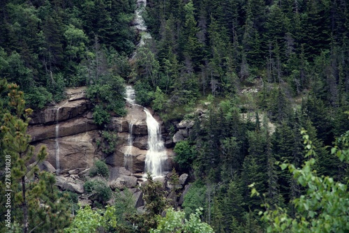 View of Mountainside waterfall with bridge and a train crossing the bridge, outside Skagway Alaska