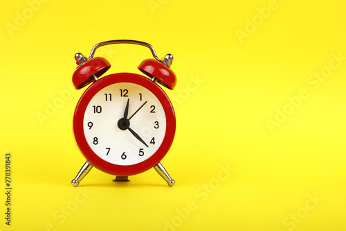Close up one red alarm clock over yellow background