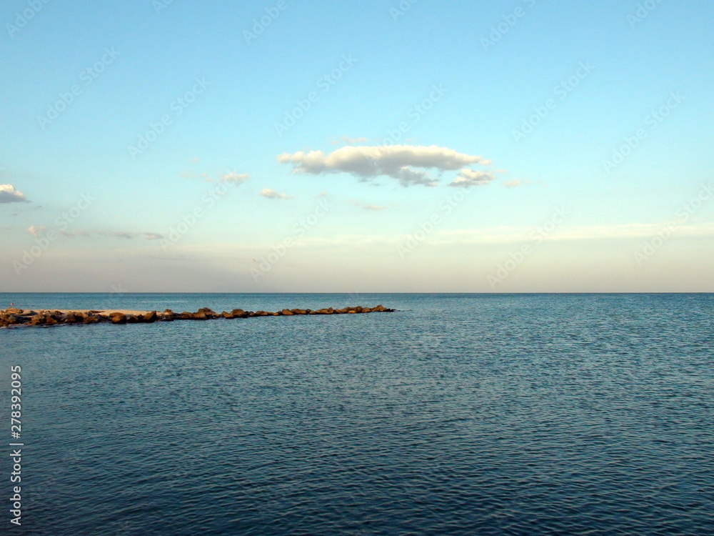 The panorama of the evening sky is decorated with rainbow colors in the sunset over the boundless sea surface, barely covered with ripples. The panorama of the evening sky is decorated with rainbow colors in the sunset over the boundless sea surface, barely covered with ripples.