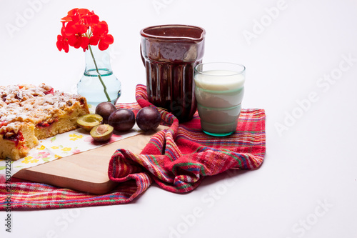 Plum cake and cup of milk on white. photo