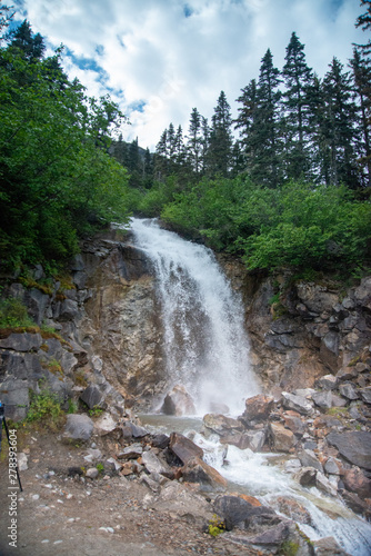 Waterfall outside of skagway alaska, with pine trees and jagged rocks