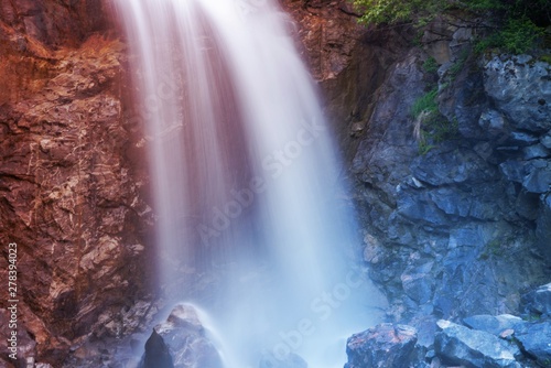 Waterfall outside of skagway alaska  with pine trees and jagged rocks