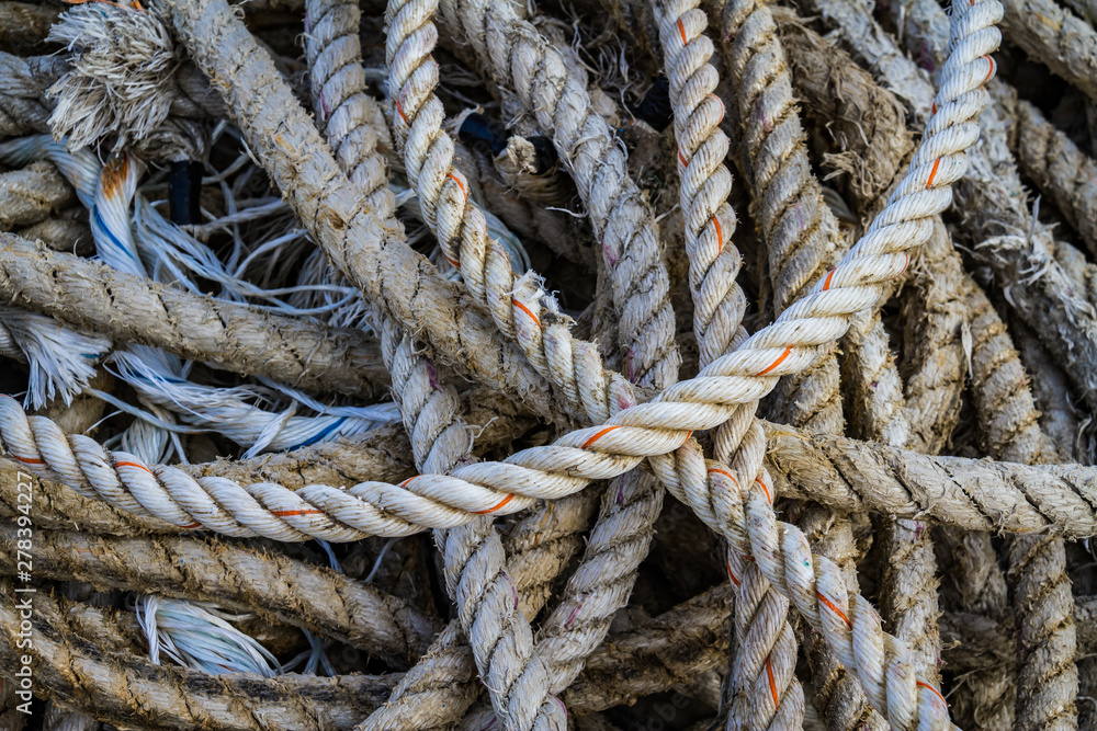 Nautical background of a detail of old frayed boat rope twisted in a pile.