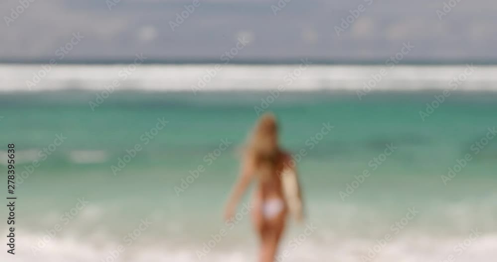 Out of focus blurry image. Young modern woman with sporty body in sexy bikini walk on ocean beach with short surf. Tourist urban lifestyle girl holiday. Summer vacation concept. Internet online work. Out of focus blurry image. Young modern woman with sporty body in sexy bikini walk on ocean beach with short surf. Tourist urban lifestyle girl holiday. Summer vacation concept. Internet online work.