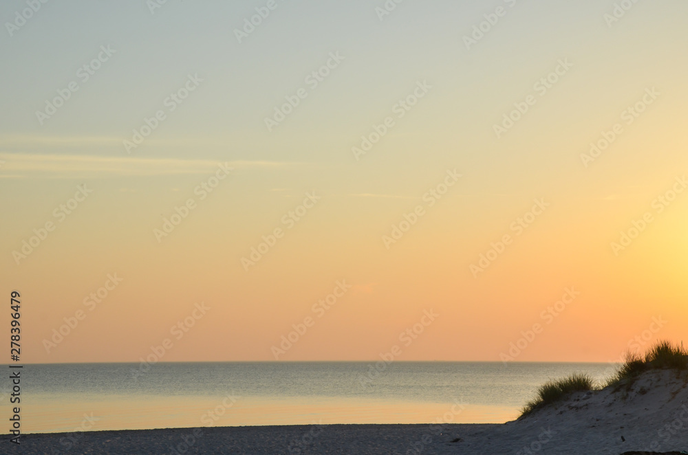 Colorful sky by a sandy beach by sunset