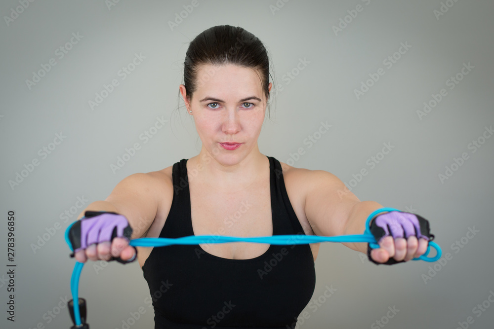 beautiful white caucasian girl in a black T-shirt on fitness holding a jump rope on outstretched arms. Isolated on gray studio background beautiful white caucasian girl in a black T-shirt on fitness holding a jump rope on outstretched arms. Isolated on gray studio background