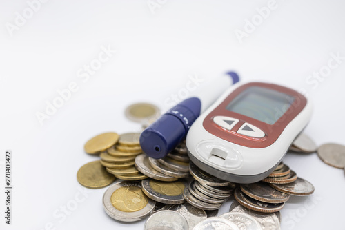 Close up of Glucode meter with lancet for check blood sugar level on pile of coins on white background. Money, Medicine, diabetes, glycemia, health care and money concept. photo