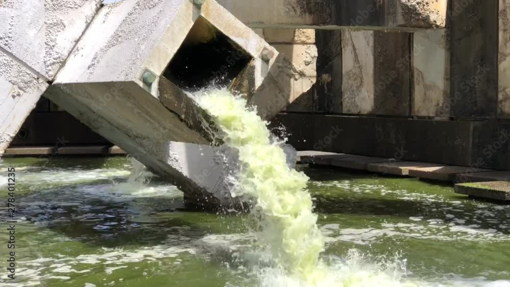 4K HD video of water green with algae pouring out of a square tube from