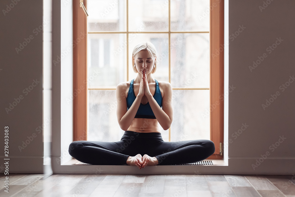 Portrait of a beautiful healthy young woman yoga instructor meditating during class. Concept of appeasement and relaxation, namaste, silhouette Portrait of a beautiful healthy young woman yoga instructor meditating during class. Concept of appeasement and relaxation, namaste, silhouette