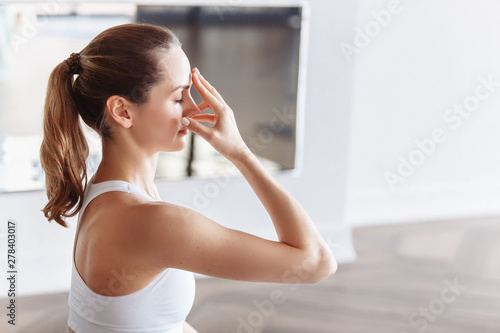 Side view of a young woman doing pranayama with her eyes closed. The concept of meditation and the rise of the kundalini photo