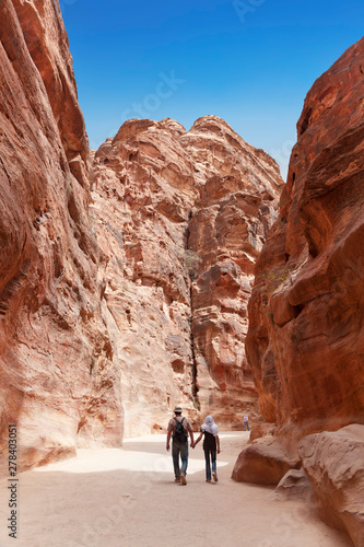 Tourists in narrow passage of rocks of Petra canyon in Jordan. Petra has been a UNESCO World Heritage Site since 1985. Way through Siq gorge to stone city Petra