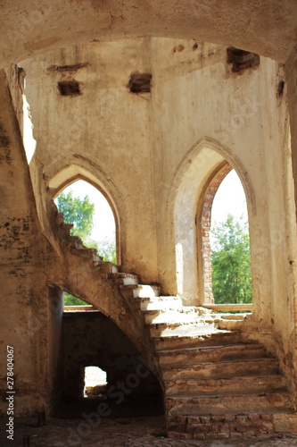 Fototapeta Naklejka Na Ścianę i Meble -  Spiral stone staircase and arch windows of the old ruined Lutheran church built in the Gothic style. Journey to the cantons of the Volga Germans, Saratov region. Selective focus.
