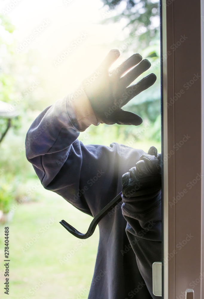 A burglar tries to break into a house in bright daylight. Concept crime. A burglar tries to break into a house in bright daylight. Concept crime.