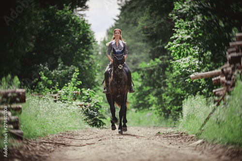 portrait of attractive woman galloping on black hanoverian stallion horse