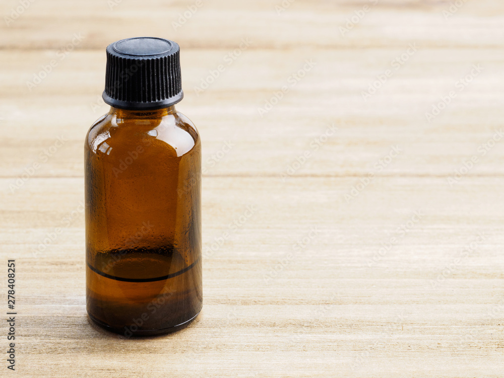 Empty yellow glass bottle with black cap for aromatherapy products on wooden background Empty yellow glass bottle with black cap for aromatherapy products on wooden background