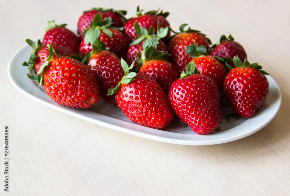 Fresh strawberries on a white plate on a wooden light background, copy space. Strawberry background. Sweet, juicy, ripe strawberries. Harvest of organic local strawberries. Healthy food with vitamins Fresh strawberries on a white plate on a wooden light background, copy space. Strawberry background. Sweet, juicy, ripe strawberries. Harvest of organic local strawberries. Healthy food with vitamins