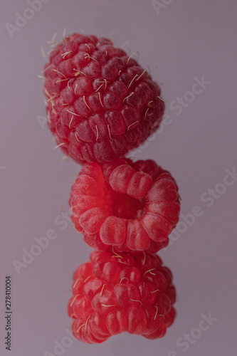 falling red raspberries on pink background