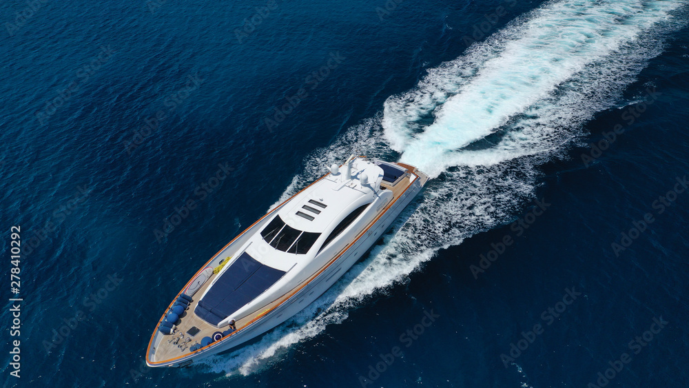 Aerial drone tracking photo of luxury yacht with wooden deck cruising in deep blue waters of Mykonos island, Cyclades, Greece Aerial drone tracking photo of luxury yacht with wooden deck cruising in deep blue waters of Mykonos island, Cyclades, Greece
