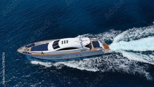 Aerial drone tracking photo of luxury yacht with wooden deck cruising in deep blue waters of Mykonos island, Cyclades, Greece © aerial-drone