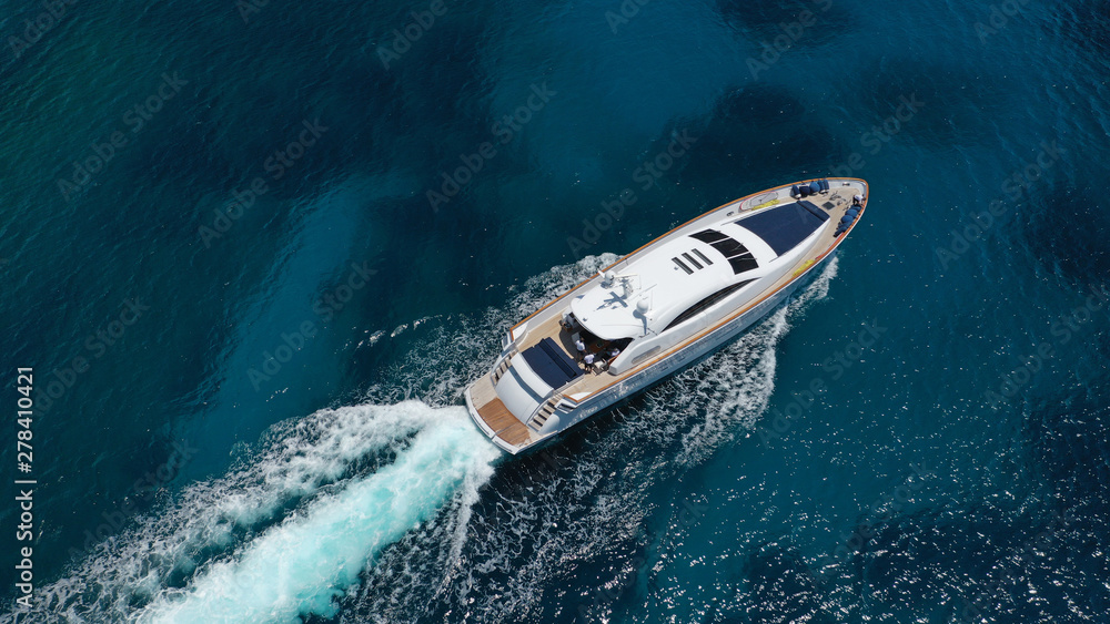 Aerial drone tracking photo of luxury yacht with wooden deck cruising in deep blue waters of Mykonos island, Cyclades, Greece Aerial drone tracking photo of luxury yacht with wooden deck cruising in deep blue waters of Mykonos island, Cyclades, Greece