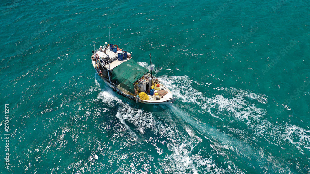 Aerial top view photo of big traditional fishing boat cruising in emerald sea near port of Paros island, Cyclades, Greece