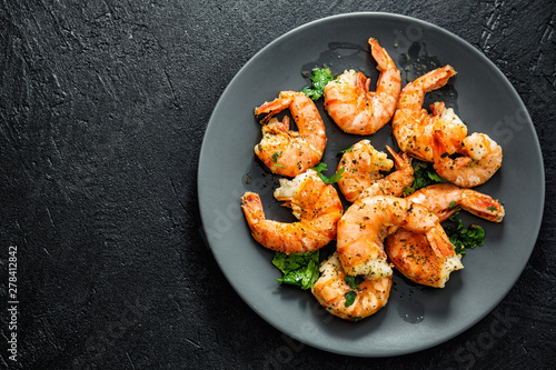 Grilled shrimps on plate on dark background