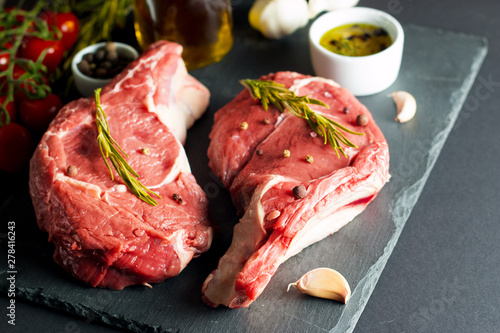 Raw fresh meat, beef and pork steak, ribeye, with rosemary, pepper and salt. Marbled beef cutlet with salt and spices.