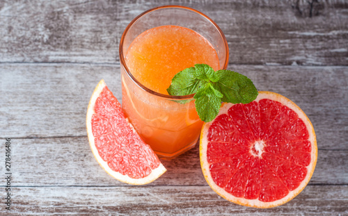 A glass of ripe grapefruit with juice on wooden table close-up