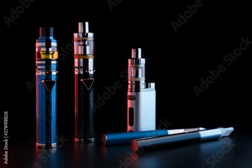 electronic cigarettes or vaping devices on black background. Toned light photo