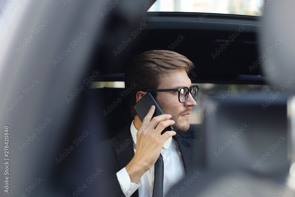 Thoughtful confident businessman talking on the phone while sitting in the car. Thoughtful confident businessman talking on the phone while sitting in the car.