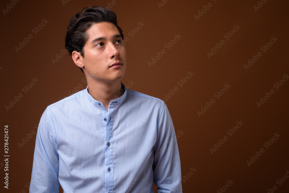 Young multi-ethnic handsome businessman against brown background Young multi-ethnic handsome businessman against brown background