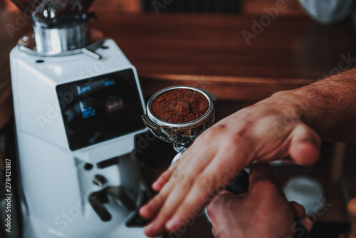 Barista tapping the filter holder while making ground coffee smooth