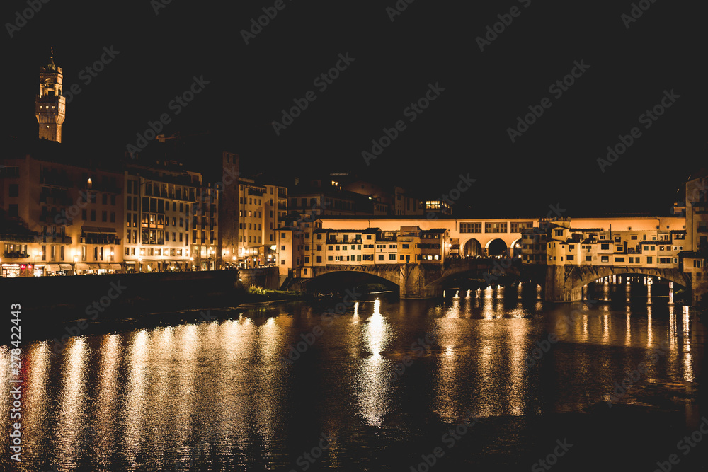 Ponte Vecchio and the buildings close by at night reflecting on the river Arno. Florence, Italy.
