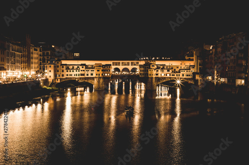 Ponte Vecchio and the buildings close by at night reflecting on the river Arno. Florence, Italy.